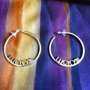 Gold Color Hoop Earrings With The Word Lucky And A Small 4 Leaf Clover.EUC